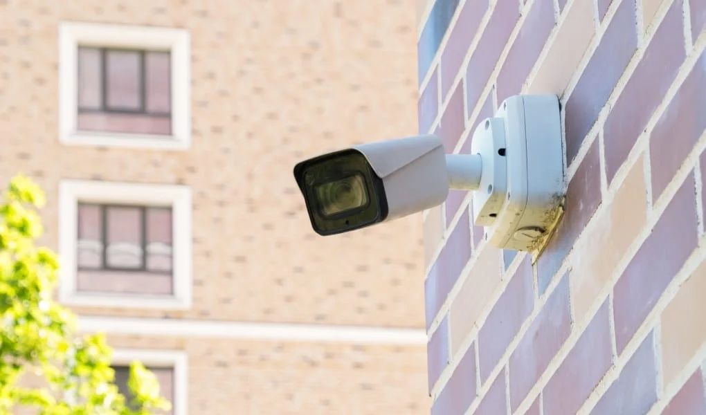 Small white CCTV cameras on a pole against the background of a modern high-rise building. Security, video surveillance, face recognition. Providing security in a residential area.