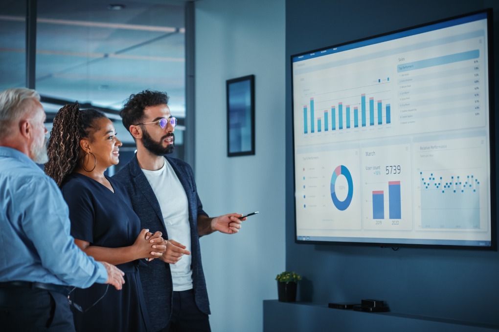 Company Operations Manager Holds Meeting Presentation. Diverse Team Uses TV Screen with Growth Analysis, Charts, Statistics and Data. People Work in Business Office.