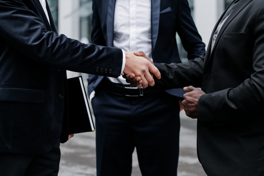 Handshake of business partners. Three businessmen close-up