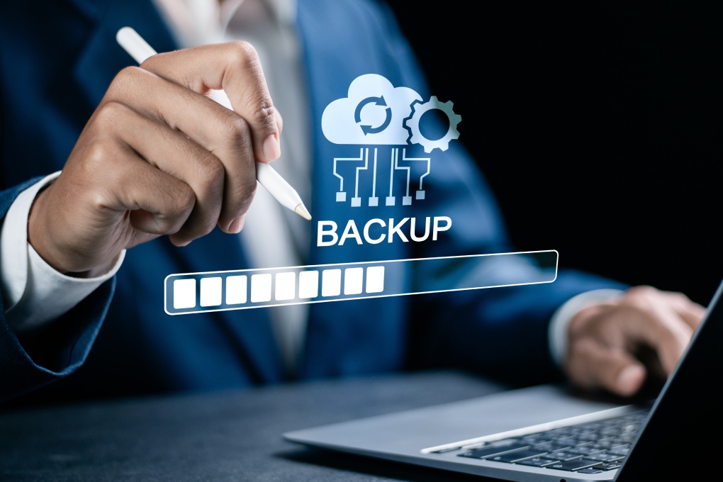 Backup concept, Online digital data storage and connection service. Businessman use laptop with Backup status bar for data backup management.