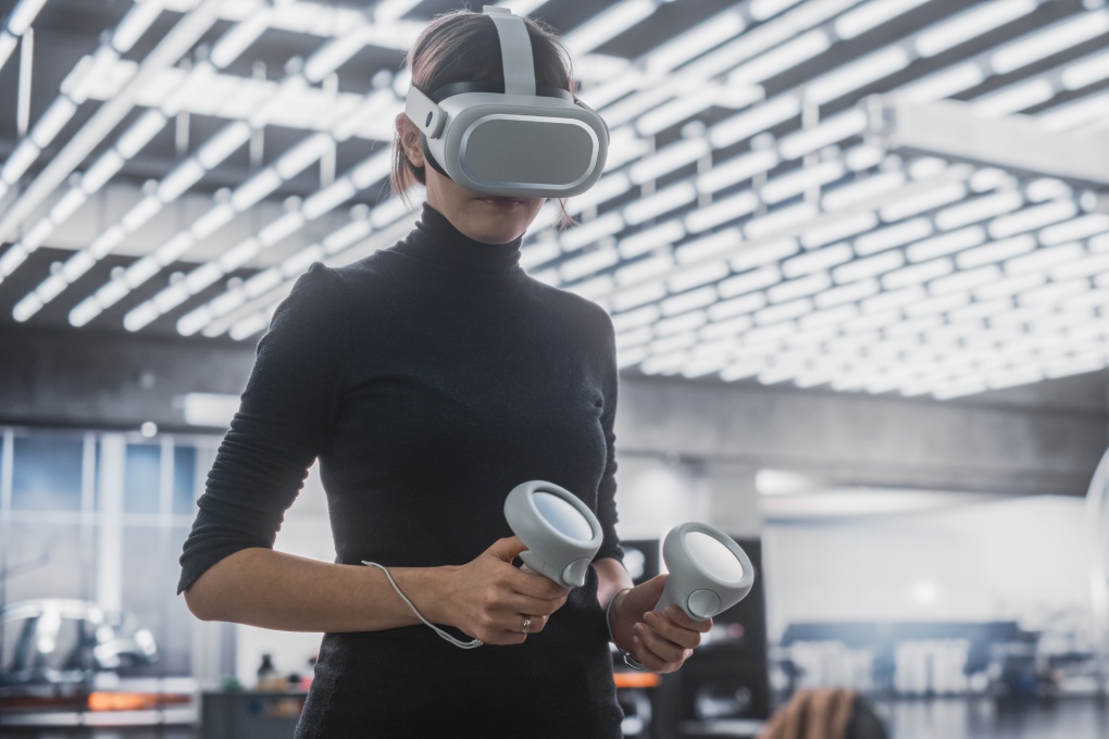 Female Specialist Using a Virtual Reality Headset and Controllers at Work in a Technology Research and Development Office. VR Software Engineer Programming a Virtual Game or Augmented Reality Solution