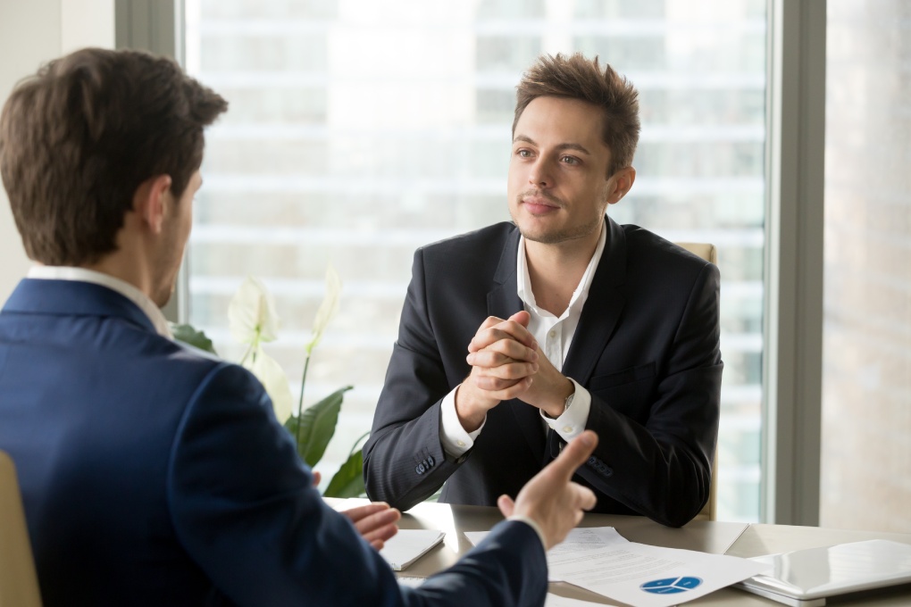 Attentive businessman listening to business partner talking during negotiations, thinking over his ideas, business team discussing project, financial adviser consulting client at meeting in office