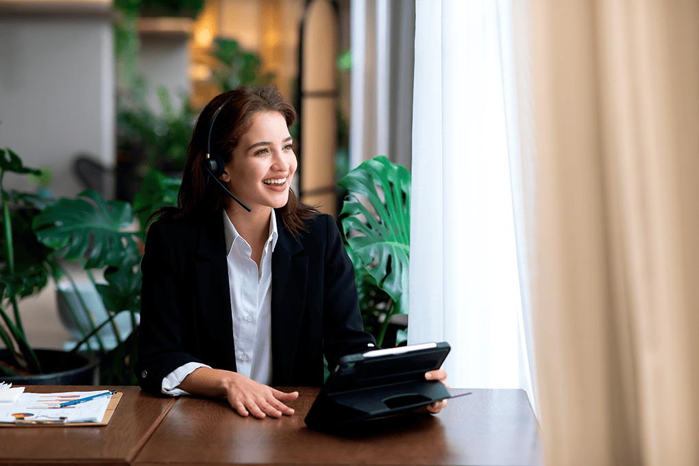 Woman smiling and doing VoIP call with headphones an tablet.